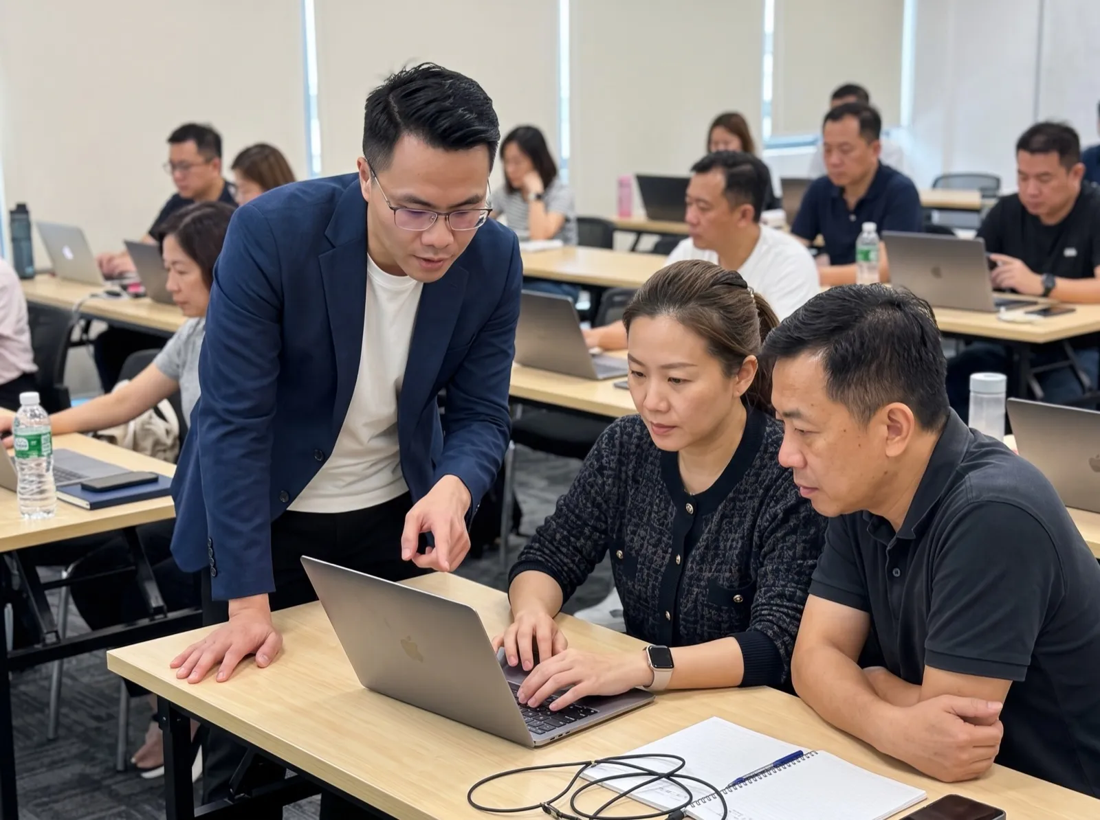 导师俯身指导两位学员在手提电脑上操作